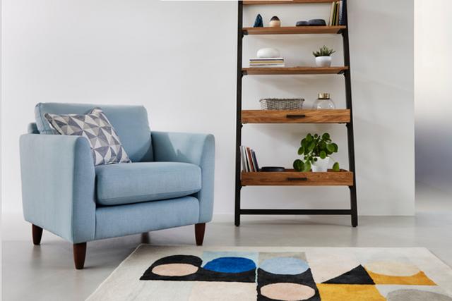 Pale blue snuggler chair with geometric rug.