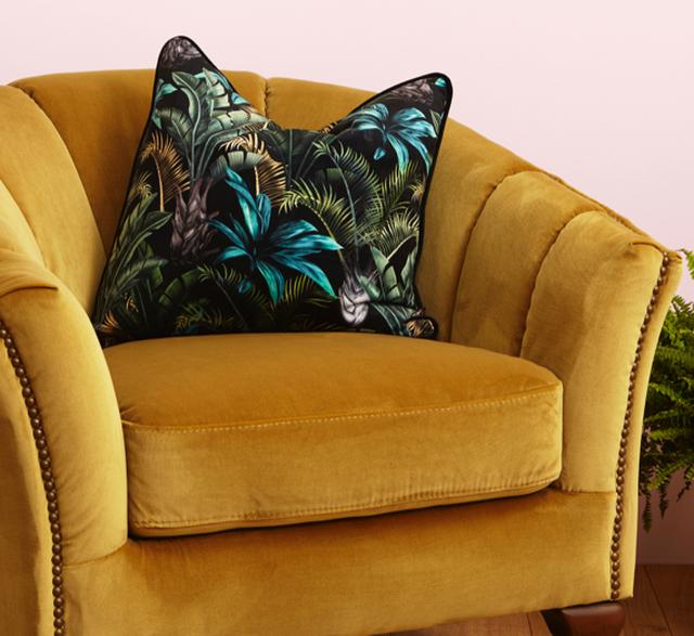 Botanical pattern cushion on yellow velvet chair.
