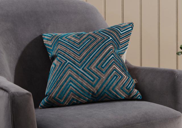Geometric teal and taupe cushion in grey bedroom